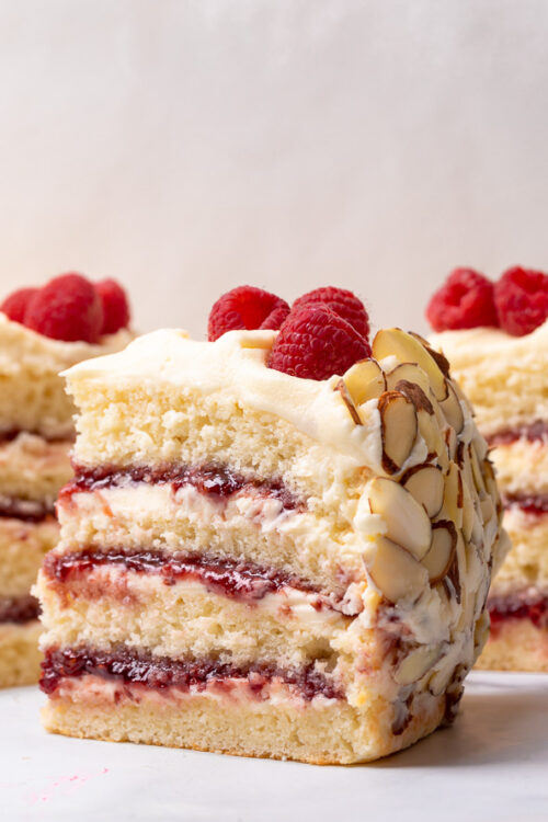 This Almond Raspberry Cake with White Chocolate Amaretto Buttercream Frosting is a total showstopper! Featuring four layers of light and fluffy almond cake, raspberry filling, and creamy white chocolate amaretto cream, this cake is decadently sweet! A must try if you love raspberry almond desserts!